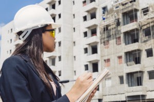 Empresa de Segurança do Trabalho 2 african american lady safety helmet writing notepad near building construction 23 2148039982